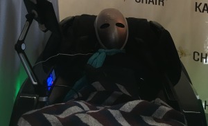 A mystery guest, rocking the mask in a massage chair. Who could it be?  Photo by Nina Herzog.