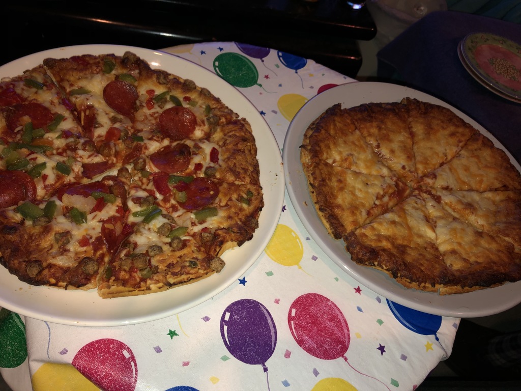 A duo of frozen pizzas, with party plates in the background.  Photo by Karen Salkin.