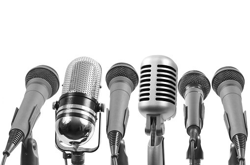 Six microphones isolated on white. The 4th from left is not a Shure mic.