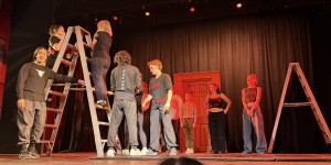 An audience member on the ladder, about to do a trust fall with the troupe. Photo by Karen Salkin.